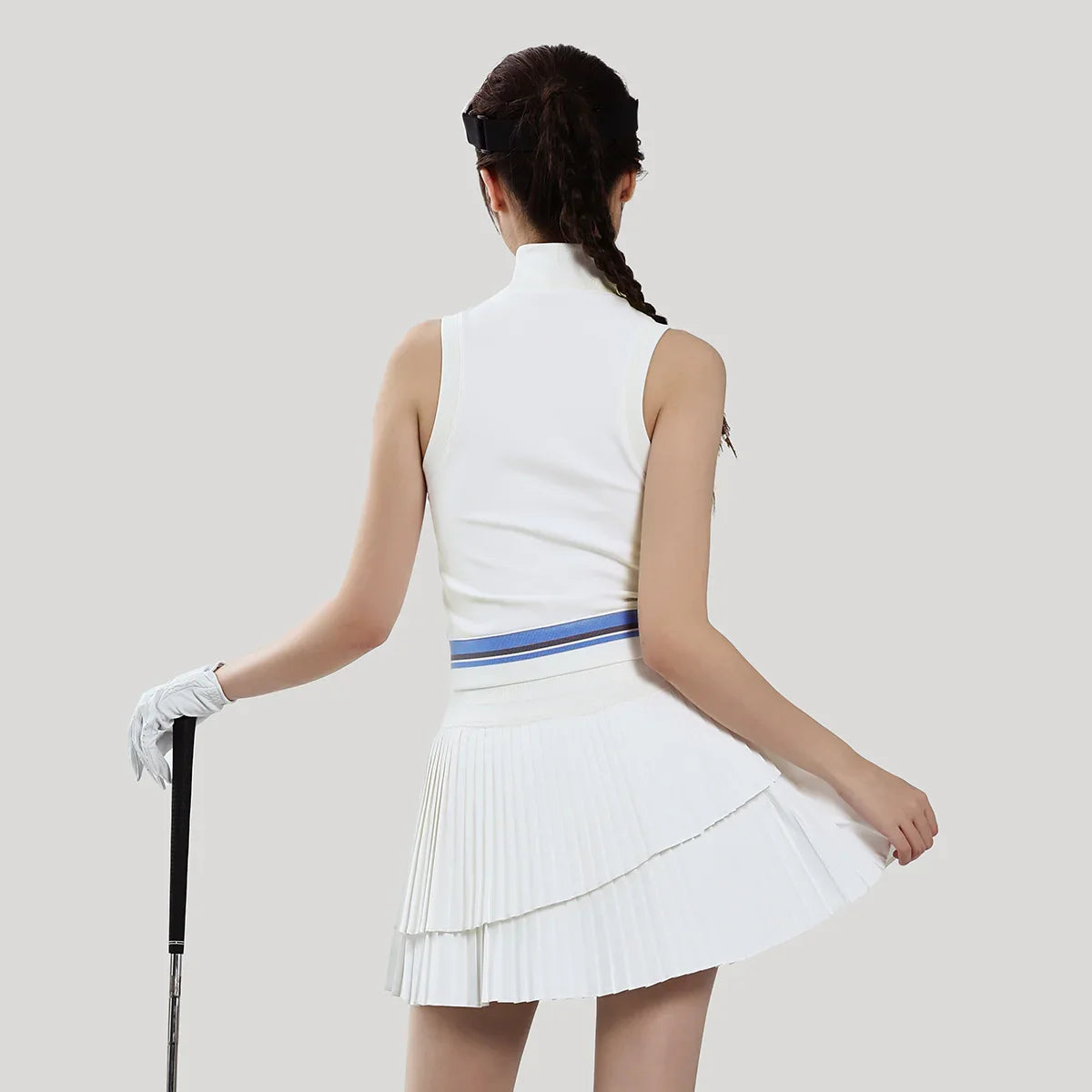 Woman in a white golf outfit with a blue stripe on a light gray background