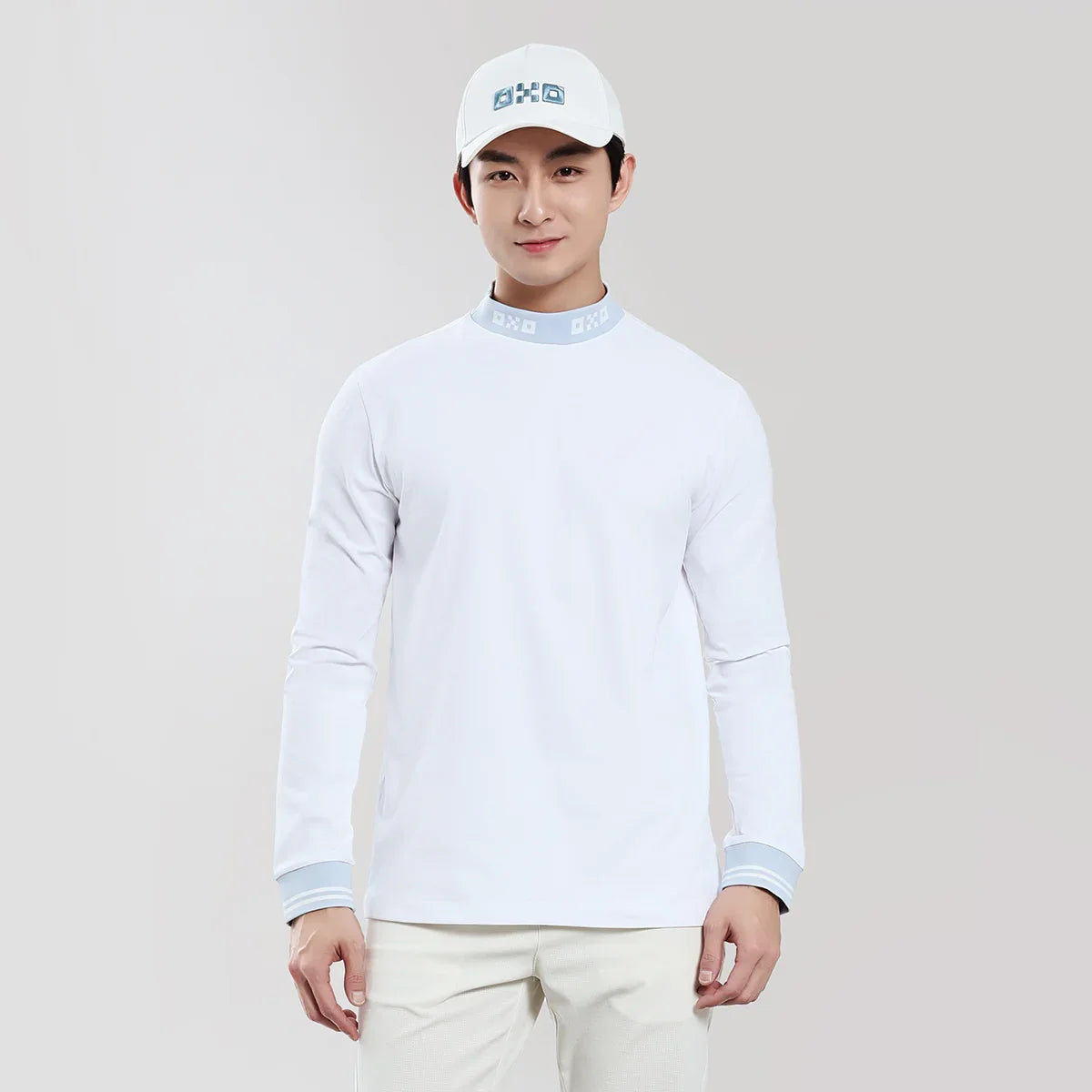 Person wearing a white long-sleeve shirt and cap on a plain background