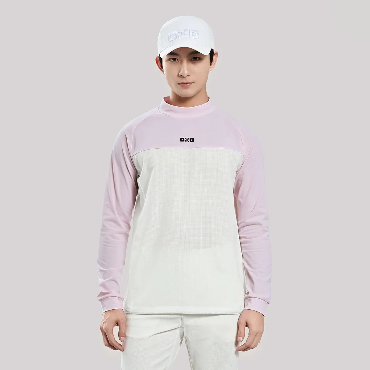 Person wearing a light purple and white long-sleeve shirt with a cap on a gray background