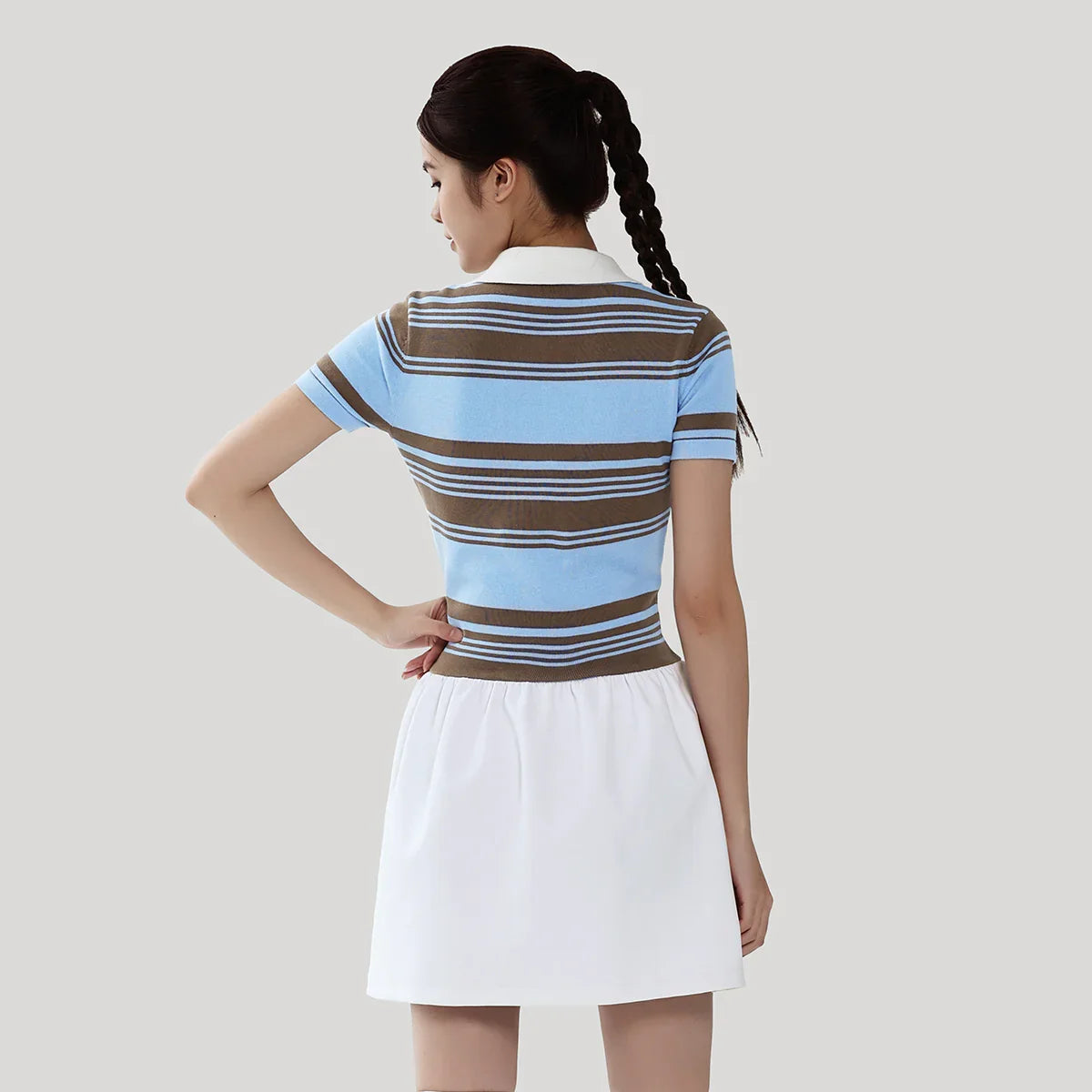 Woman wearing a striped polo shirt and white skirt on a plain background