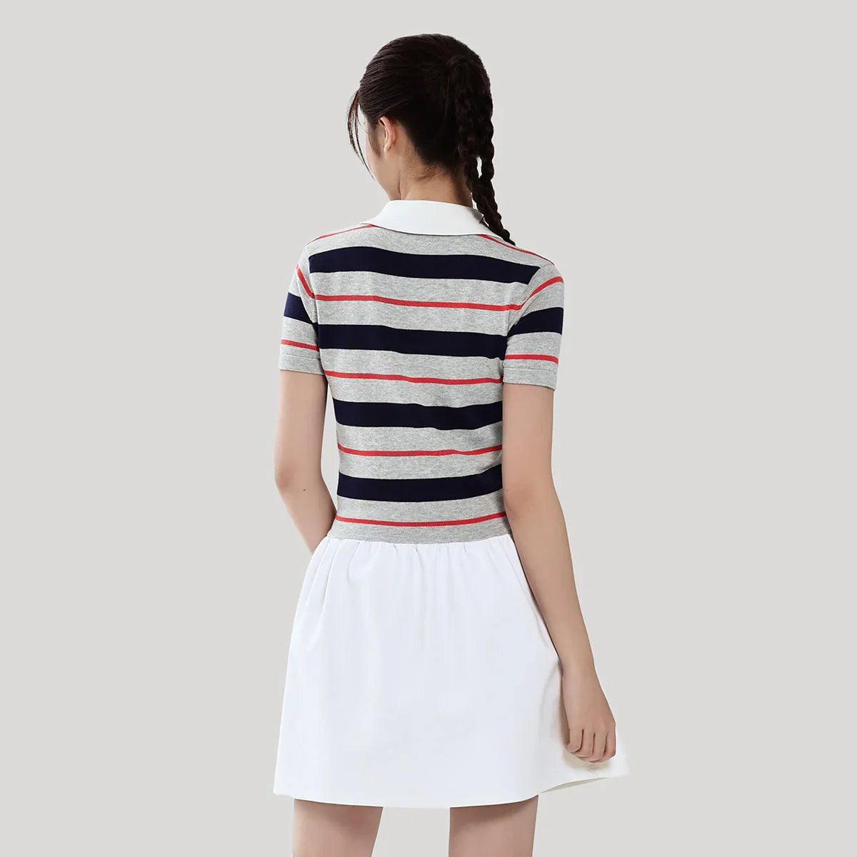 Woman wearing a striped shirt and white skirt on a plain background
