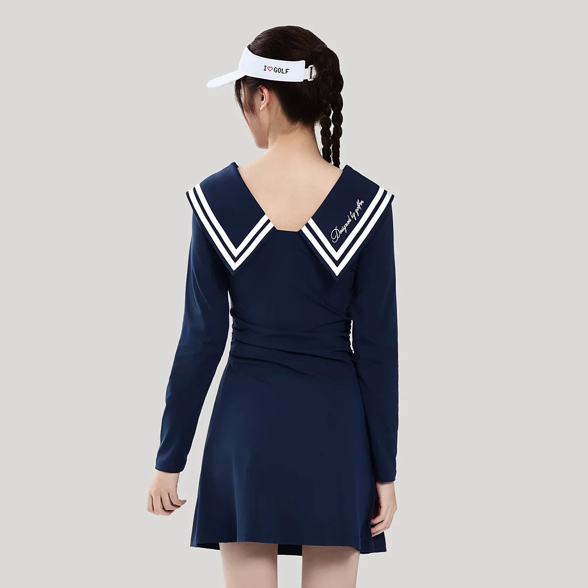 Woman wearing a navy blue dress with white trim on a gray background