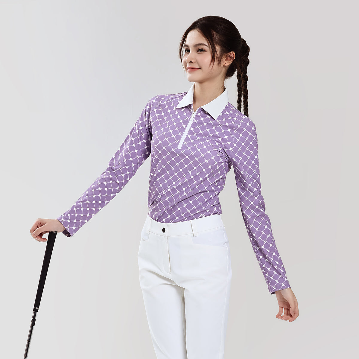 Woman wearing a purple checkered shirt and white pants on a plain background