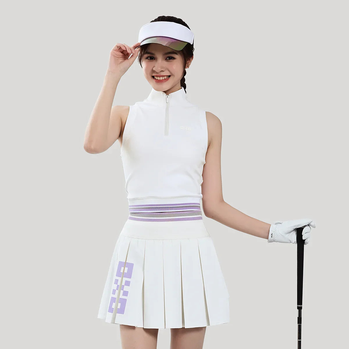 Woman in golf attire with a white outfit and visor on a plain background
