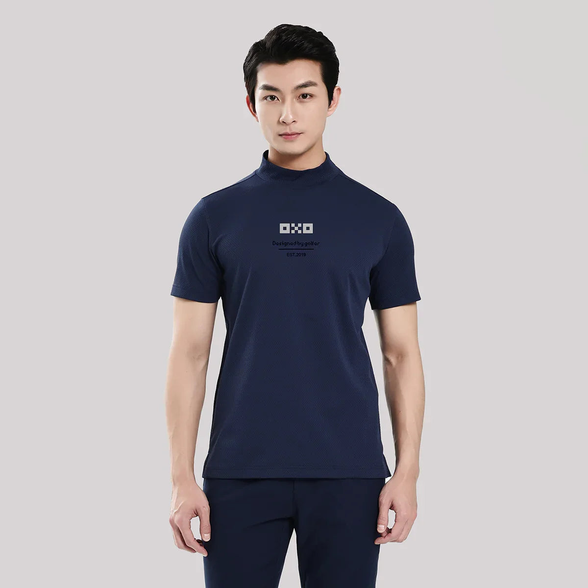 Man wearing a navy blue t-shirt with a logo on a light gray background