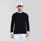 Person wearing a black long-sleeve shirt, white pants, and a white cap with a logo on a light gray background