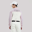 Person wearing a light pink and white long-sleeve shirt with a logo on the back, standing against a plain background.