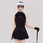 Woman in black sleeveless top and skirt with visor holding a golf club on a light gray background