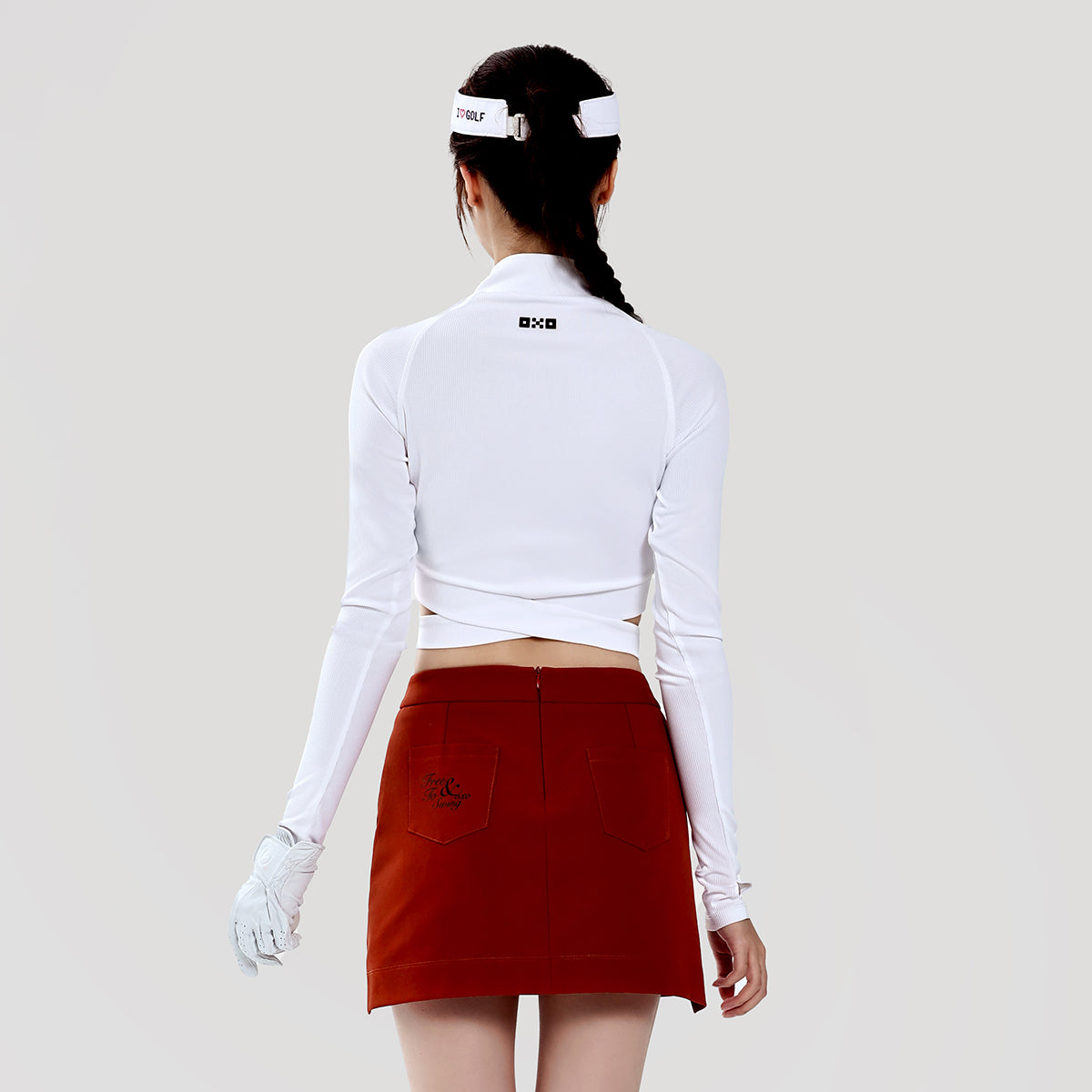 Person wearing a white long-sleeve top and red skirt with a white visor on a plain background
