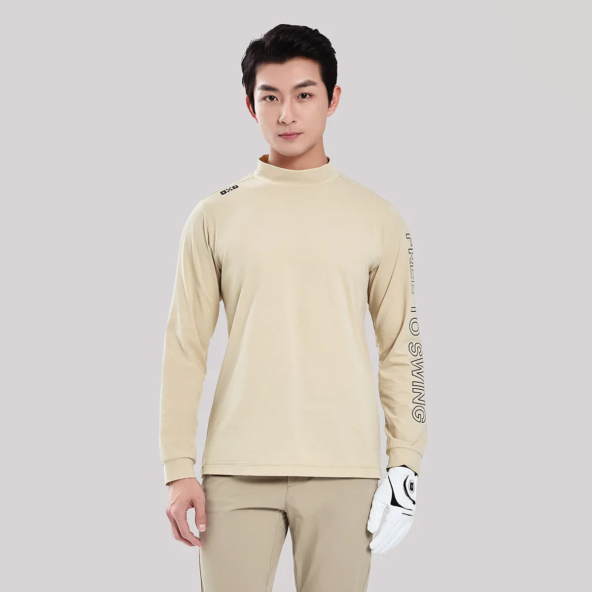 Man wearing a beige long-sleeve shirt with text on sleeves against a light gray background