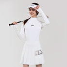 Woman in white tennis outfit holding a racket against a plain background