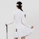 Woman wearing a white tennis dress with a headband and holding a tennis racket on a light gray background