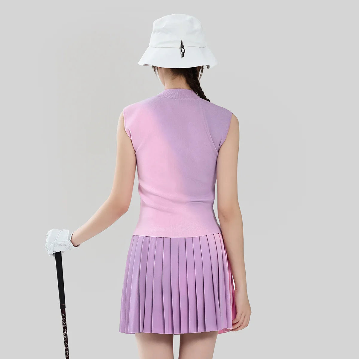 Person wearing a pink golf outfit with a white hat on a gray background