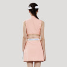 Woman wearing a pink golf outfit with a visor on a light gray background