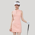 Woman in a pink golf dress with a white visor and golf club on a gray background