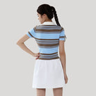 Woman wearing a striped polo shirt and white skirt on a plain background