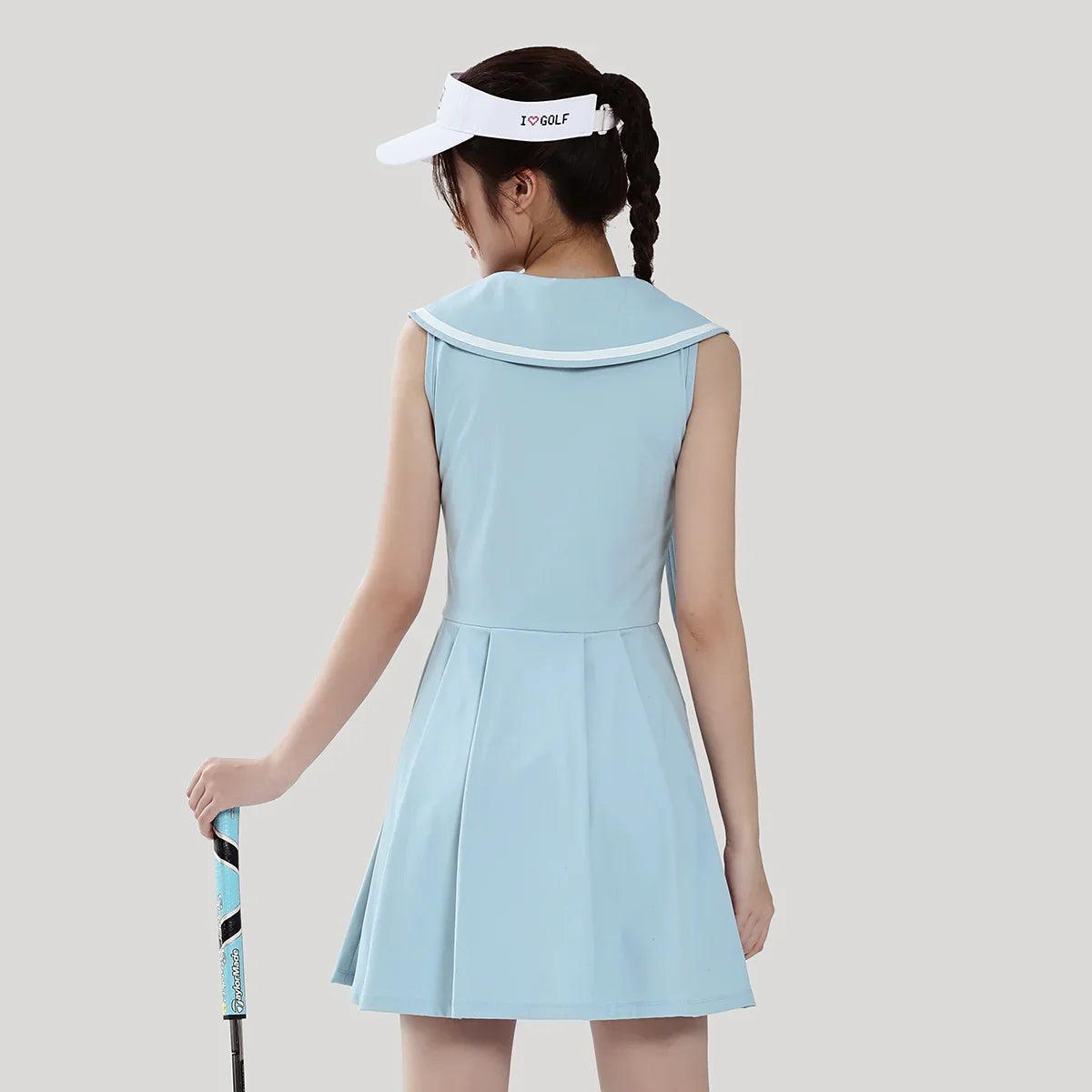 Woman wearing a light blue dress and white visor with 'I'm GOLF' text on a plain background