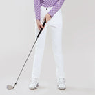Person holding a golf club in a white outfit on a light gray background