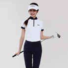 Woman in golf attire holding a golf club on a plain background