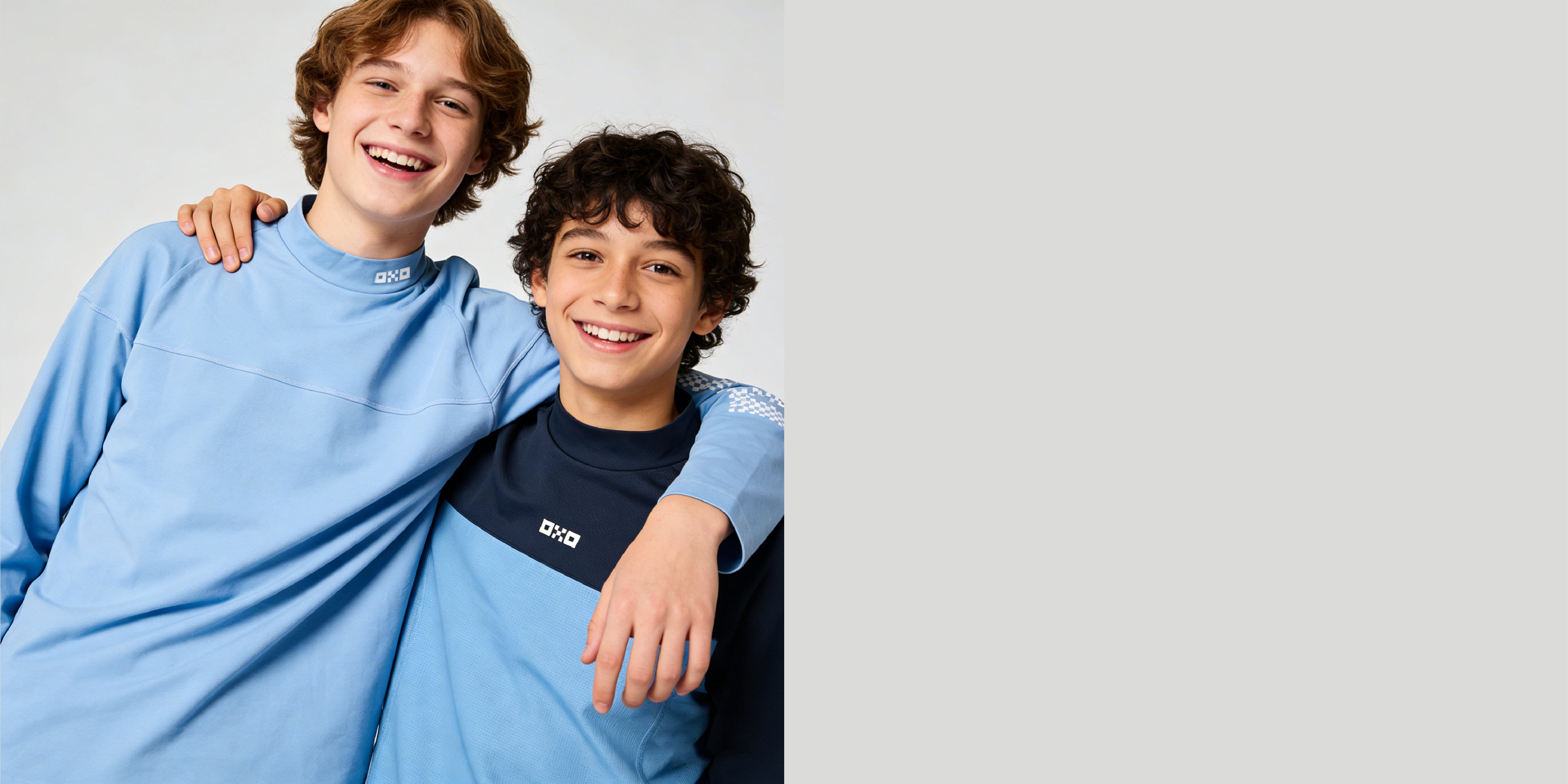 Two people wearing blue and black sweatshirts with a brand logo on a light gray background