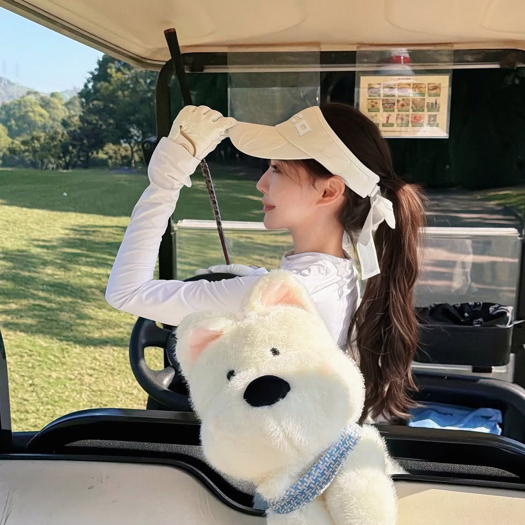 Woman in a golf cart with a large teddy bear in the foreground