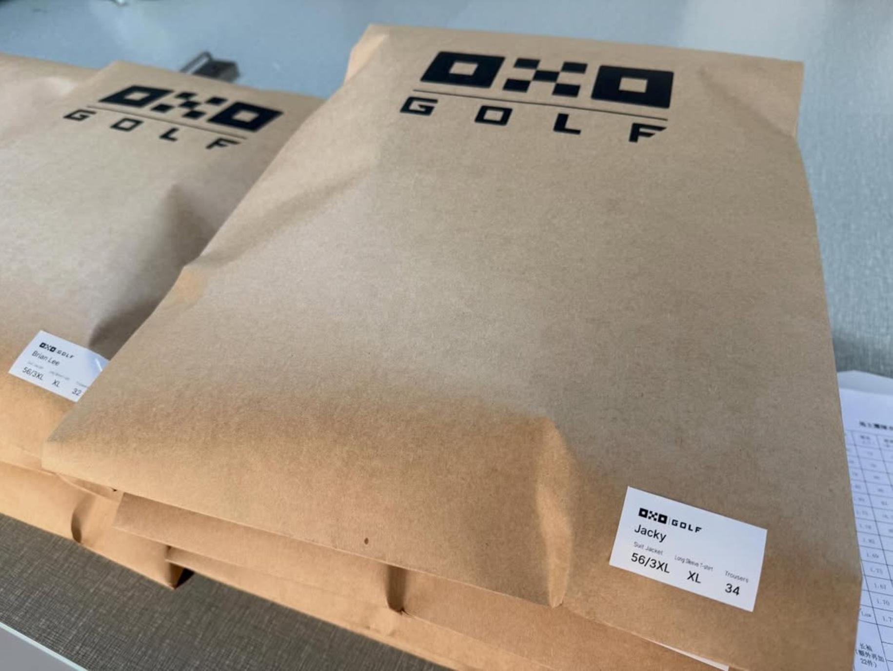Two brown OXO Golf packages on a gray surface