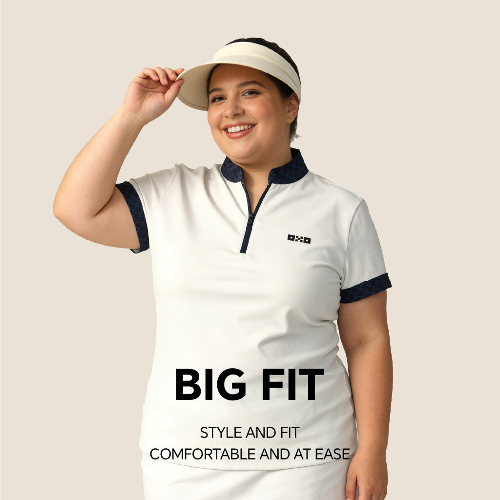 Woman wearing a white outfit with navy accents and a visor, standing against a plain background.