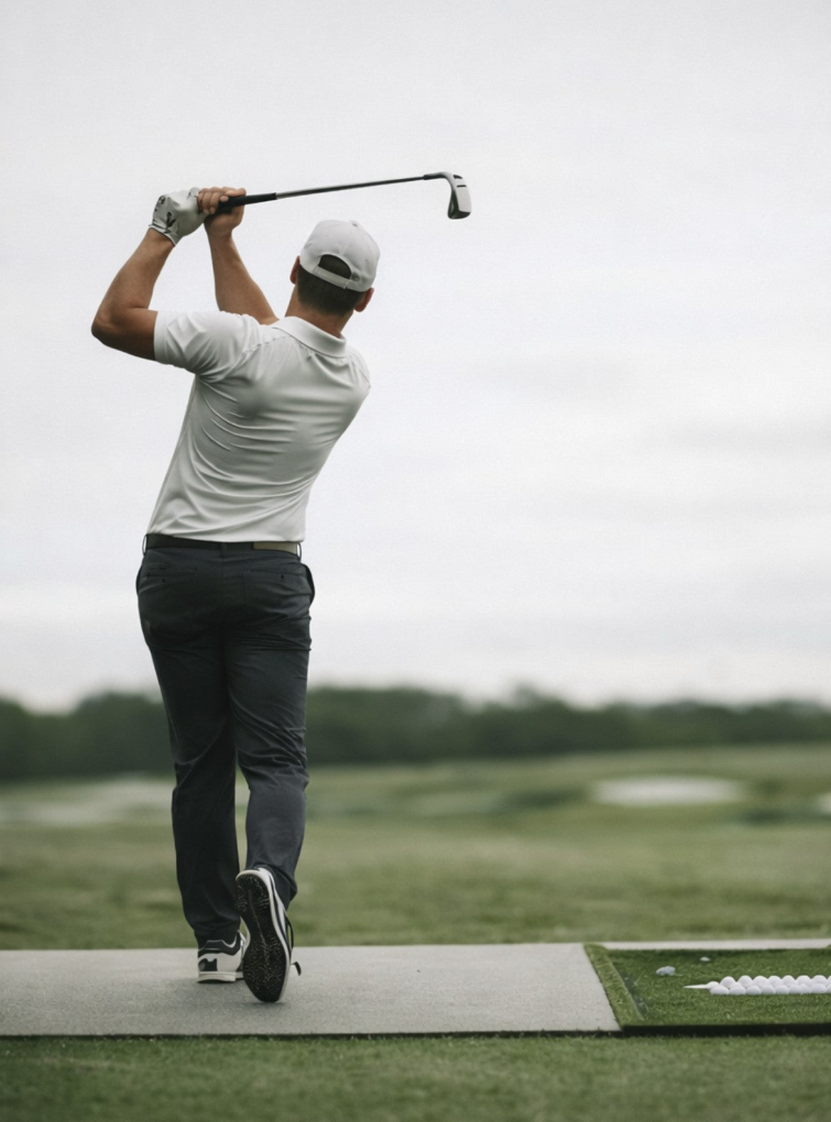 Man playing golf on a course with a cloudy sky